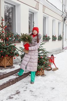 A bright woman in winter clothes walks around the city decorated for Christmas. Lifestyle in the winter season.