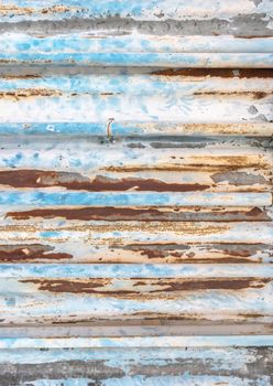 Old corrugated metal texture with rust spots on surface and peeled-off paint.