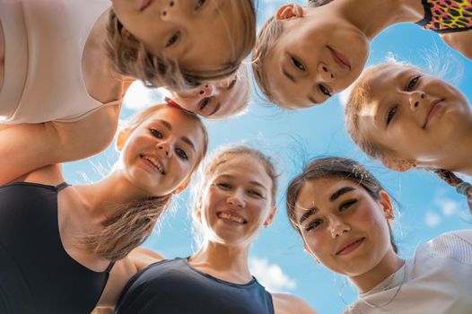 Group of children and young girls with female coach in the circle as friendship.