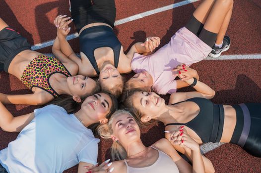 Group of children and young girls with female coach in the circle as friendship.