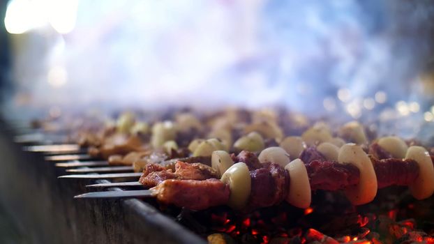 Grilled kebab cooking on metal skewer close up. Roasted meat cooked at barbecue. Grill on charcoal and flame, picnic, street food. High quality photo