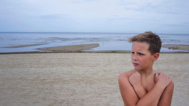 Portrait of a handsome boy on the Baltic coast in cloudy weather. The boy is looking away.