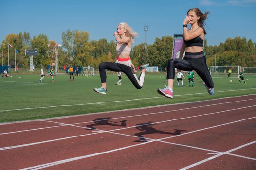 Two athlete young woman runnner are training at the stadium outdoors