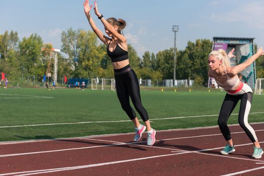 Two athlete young woman runnner are training at the stadium outdoors