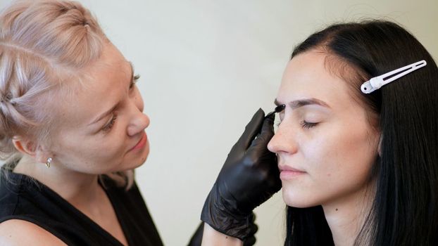 beauty saloon. the cosmetician in black rubber gloves keep a special brush and comb eyebrows. Master corrects the shape of the eyebrows. Professional care for face. High quality photo