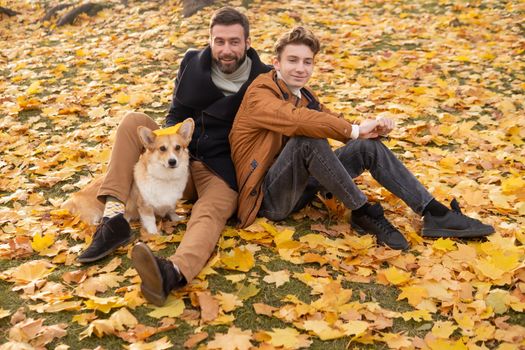 Father and son with a pet on a walk in the autumn park.