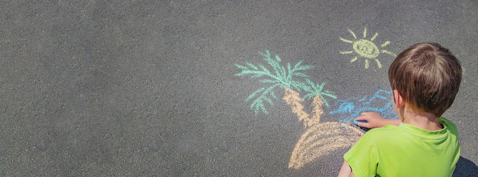 child draws with chalk on the pavement. Selective focus. nature.