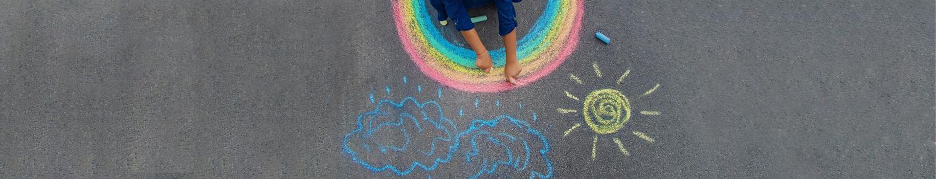 child draws with chalk on the pavement. Selective focus.