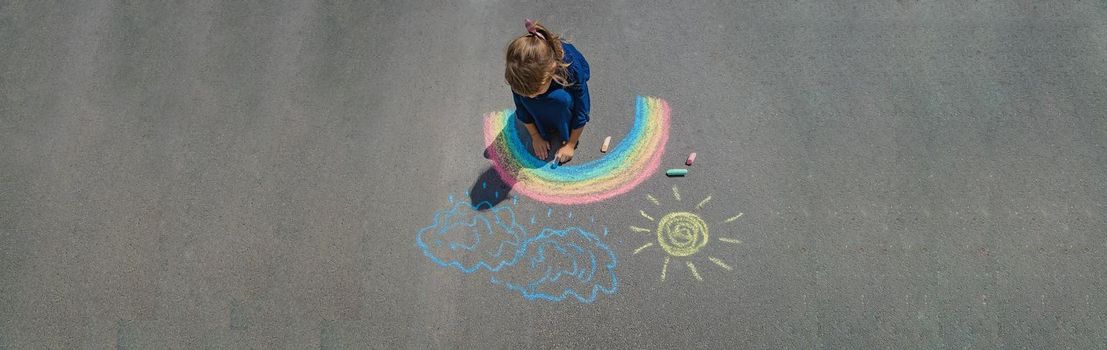 child draws with chalk on the pavement. Selective focus. nature.