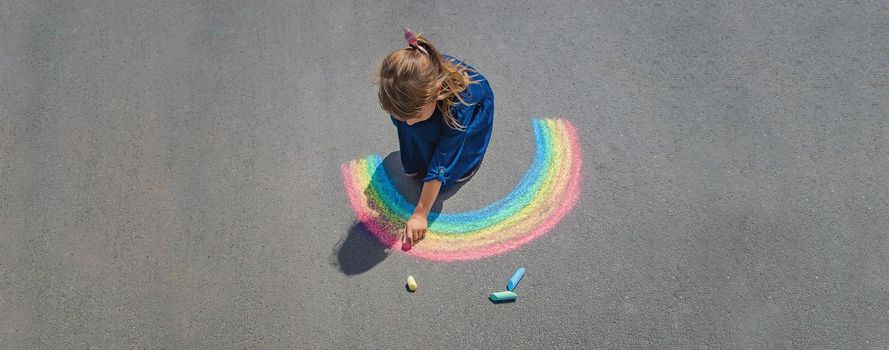 child draws with chalk on the pavement. Selective focus.