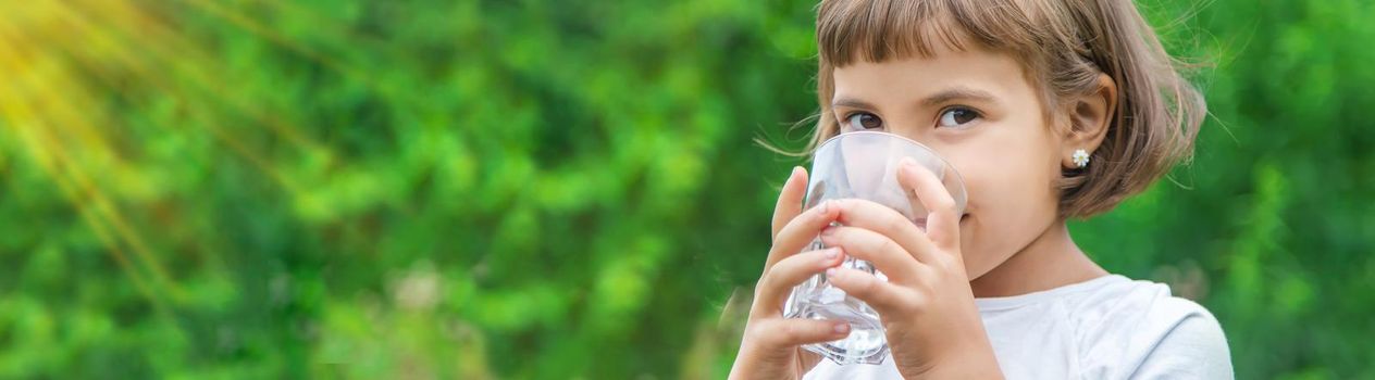 child drinks water from a glass. Selective focus. Kid.