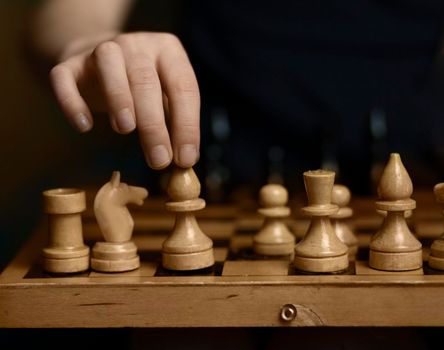 chess board white and black pieces a child's hand takes a chess piece of a white elephant with children's fingers. High quality photo