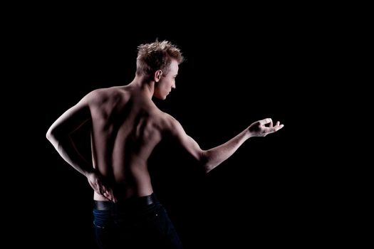 Young man naked torso in jeans in dark