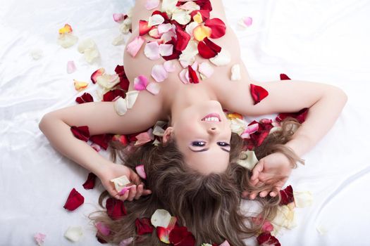 Beautiful woman lying in bed in rose petals
