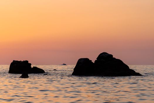 Beautiful view of orange sunset seascape with rocks in Italy. Tropical colorful sunrise landscape