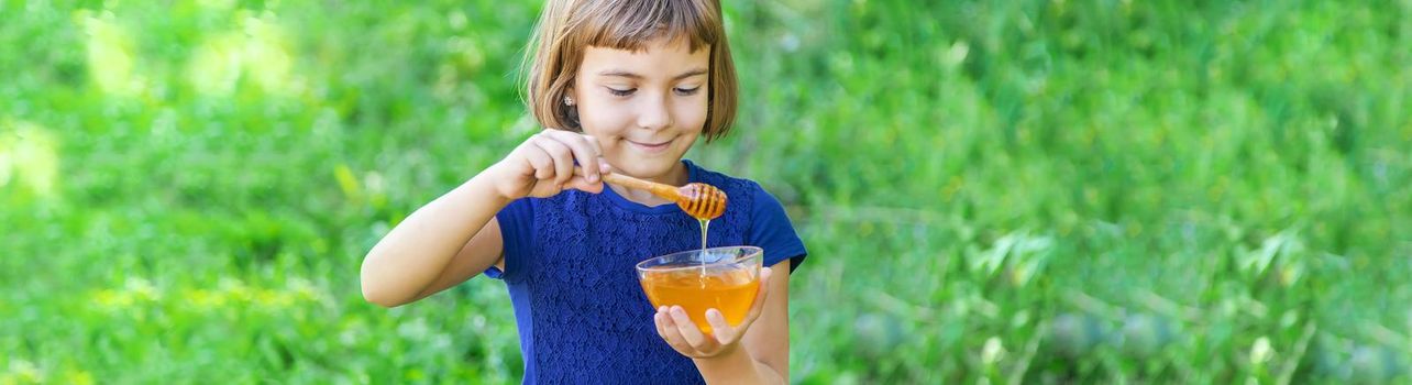 Child a plate of honey in the hands. Selective focus.