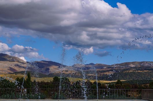 mountain landscape with cloudy storm sky and water jets in the foreground