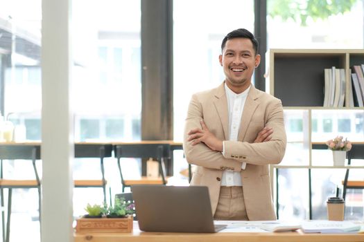 Asian businessman standing by his desk in office.