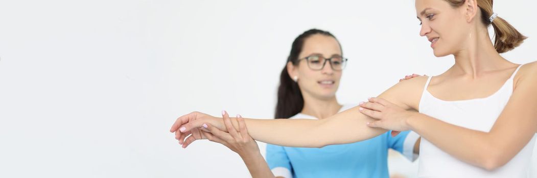 The doctor holds the hand and shoulder of a sick woman, close-up. Rehabilitation, muscle recovery, arm pain