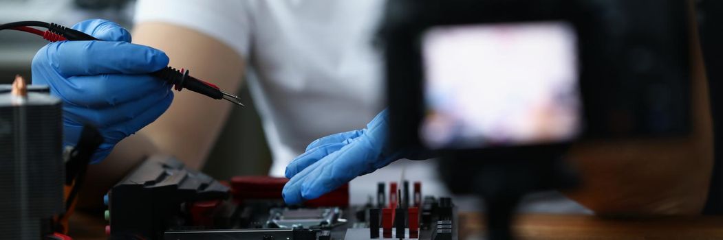 A man makes a video blog on repairing a pc, close-up, blurry. The camera is filming the repair of a digital device