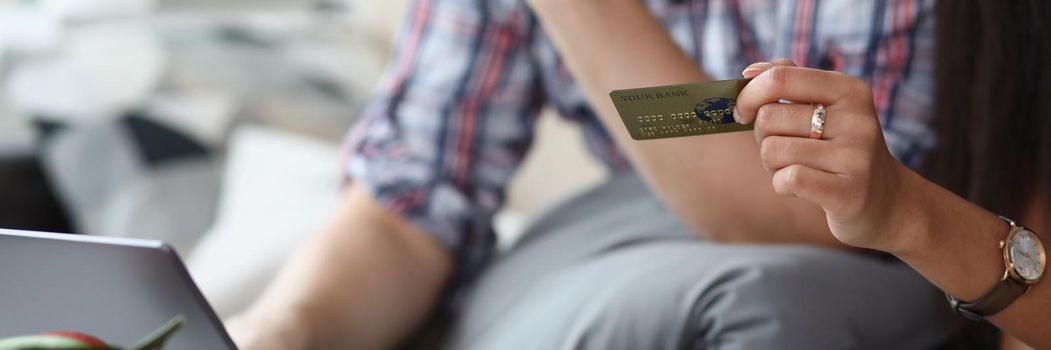 A married couple at home pays for purchases online, female hands with a credit card close-up. Ordering goods and products