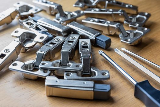 A pile of soft close cabinet door hinges and screwdrivers