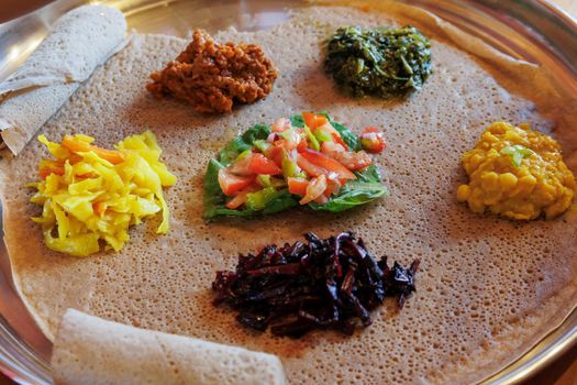 Injera served with vegetables and lentils. Injera, the staple food of Ethiopia, is a sourdough flatbread made from teff flour.