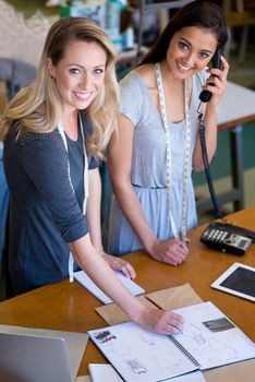 Were always busy and thats great. Portrait of two fashion designers standing at the front counter of their fabric shop