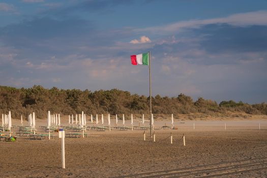 Italian flag waving in the wind on the beach at sunrise