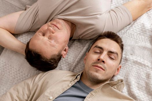 Happy gay couple with casual clothes spending time together at home. Two caucasian men relaxing. Homosexual relationships and alternative love. Cosy interior