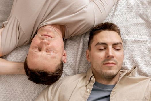 Happy gay couple with casual clothes spending time together at home. Two caucasian men relaxing. Homosexual relationships and alternative love. Cosy interior