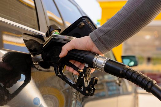 Car refuelling on the petrol station. Man refilling the car with fuel. Close up view. Gasoline, diesel is getting more expensive. Petrol industry and service. Petrol price and oil crisis concept