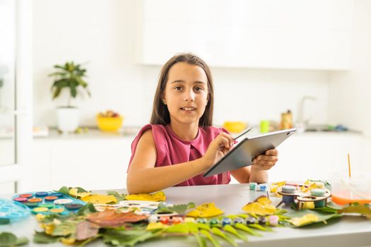 A child paints a picture of an autumn leaf with paints. Children's hands. Favorite hobby, materials for creativity. High quality photo