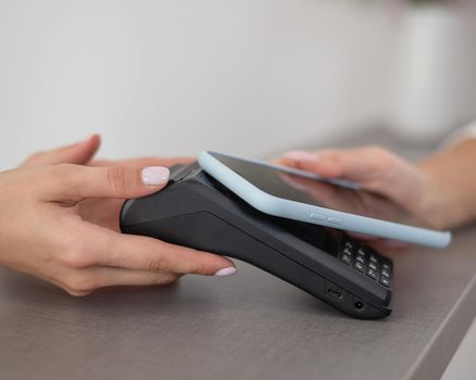 A woman pays using a non -contact payment of the NFC used by a smartphone