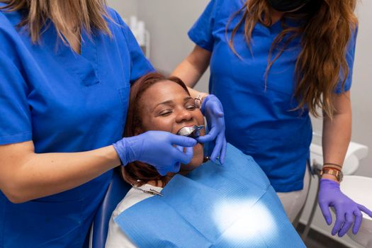 A black woman patient being put on an impression tray inside her mouth at the dental clinic