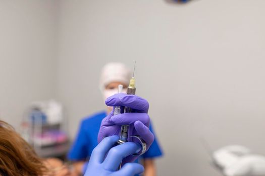 Close up view of the hands of a dentist woman holding a syringe containing anesthesia for her patient
