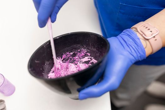 Close up view of the hands of a dentist woman mixing some plaster for her client at the dental clinic