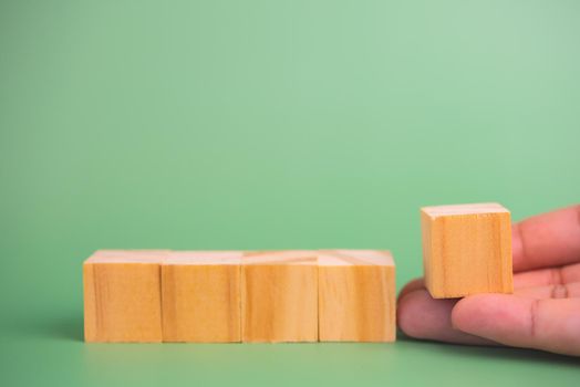 hand holding cube wood block blank on green background. copy space