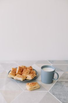 freshly baked homemade pastry on kitchen table. breakfast with puff pastry buns and milk. rustic table