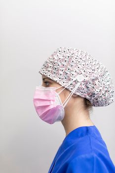 Portrait of a white dentist woman posing for the camera, wearing mask, medical hat and uniform after a day of work at the dental clinic