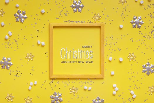 Merry Christmas greeting text in wooden frame with winter decoration on colored background. High quality photo
