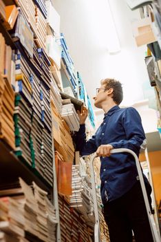 Young intelligent man looking for science materials in the local archive, prepare to write master work