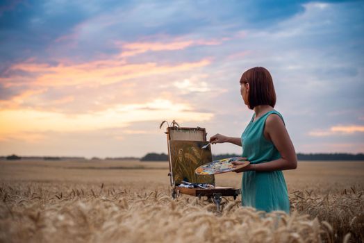 Beautiful evening in the field of ripe rye and inspired artist making final touches to her masterpiece painting