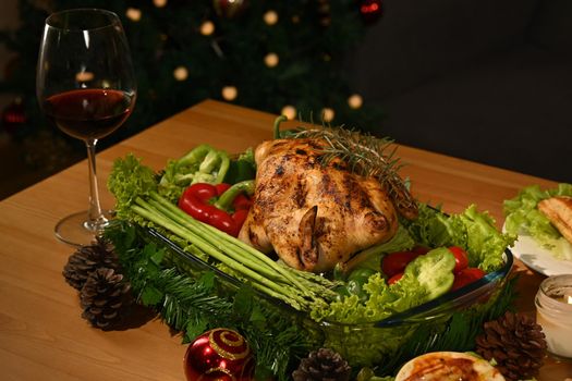 Roasted turkey, glass of red wine and sides dishes on a wooden table decorated with vegetables and candles.