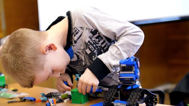 the boy of 10 years, plays in the designer from cubes, plates, circuits, wires. a small inventor creates robots, machines from different parts of the designer. children are fond of robotics, programming, modeling,. High quality photo
