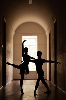 Dance in a building in front of big light window, silhouettes of two people