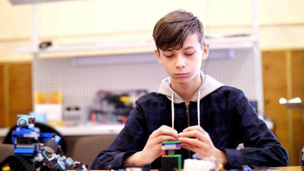 the boy of 12 years, plays in the designer from cubes, plates, circuits, wires. a small inventor creates robots, machines from different parts of the designer. High quality photo