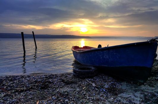 beauty sunset with the lonely blue boat on the  beach 