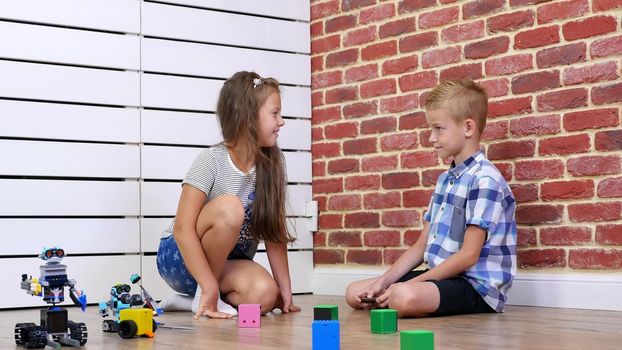 seven-year-old boy and girl play electronic robots, cars, modern toys on the radio control. new technologies in the children's gaming industry. little geniuses. High quality photo