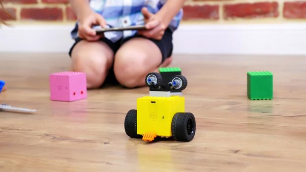 close-up, radio-controlled robot moves on floor, little geniuses, children play electronic robots, cars, modern toys on radio control. new technologies in gaming industry. High quality photo